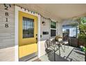 Inviting front porch with a bright yellow door, seating, and decorative details at 2818 N 19Th St, Tampa, FL 33605