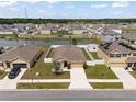 An aerial view of a suburban community featuring a pond and fenced yards at 36734 Goffaux Loop, Zephyrhills, FL 33541