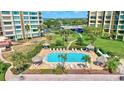 Aerial view of community pool and lounge area with manicured landscaping and multiple seating options at 736 Island Way # 303, Clearwater Beach, FL 33767