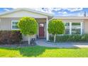 Inviting front entrance with a red door framed by manicured shrubs and brick pathway at 8392 137Th Ln, Seminole, FL 33776