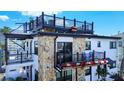 Beautiful property featuring a rooftop deck, balconies, stone accents, and lush landscaping at 9921 Gulf Blvd, Treasure Island, FL 33706