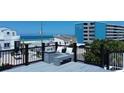 Relaxing rooftop deck with comfortable seating and ocean views of the beach and neighboring building at 9921 Gulf Blvd, Treasure Island, FL 33706