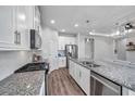 Open kitchen with white cabinets, subway tile backsplash, and a granite island with sink at 12280 Lyon Pine Ln, Odessa, FL 33556