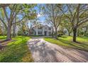 Wide brick driveway leading to a grand home, framed by mature trees and lush green lawns at 4121 Highland Park Cir, Lutz, FL 33558