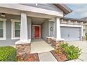 Inviting covered front porch with stone accents and a red front door enhances this home's curb appeal at 6303 Hawk Grove Ct, Wesley Chapel, FL 33545