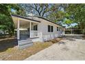 A charming white home with a covered porch and a spacious driveway leading to a carport at 8215 N 12Th St, Tampa, FL 33604