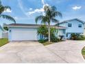 Charming light blue two-story home with lush tropical landscaping and a spacious driveway and two car garage at 8722 Hickorywood Ln, Tampa, FL 33615