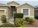 Close up of the front door and landscaping of the tan colored single-Gathering home at 11318 Laurel Brook Ct, Riverview, FL 33569