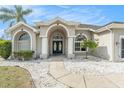 Elegant home featuring a double-door entry, arched windows, and manicured landscaping at 13403 Bolton Ct, Spring Hill, FL 34609