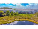 A row of townhomes feature backyard screen porches along a pond in a tranquil community setting at 17212 Balance Cv, Land O Lakes, FL 34638