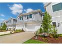 Townhomes show attached garages, grey siding, and landscaped front yards under a bright blue sky at 17212 Balance Cv, Land O Lakes, FL 34638