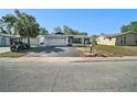 Street view showcasing the home with a two-car garage, contrasted against a bright sky and surrounding foliage at 7136 Isle Dr, Port Richey, FL 34668