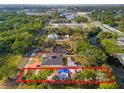 A high aerial view depicts the property's setting amidst green trees and nearby roads at 8615 Jackson Springs Rd, Tampa, FL 33615