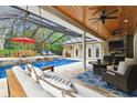 Relaxing outdoor pool area with lounge chairs, patio furniture, fireplace, and ceiling fans at 9801 Pine Leaf Ln, Dade City, FL 33525