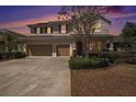 Inviting two-story home at sunset featuring a well-manicured lawn, stone accents, and a convenient two-car garage at 1018 Tracey Ann Loop, Seffner, FL 33584