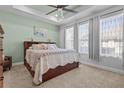 Serene bedroom featuring a tray ceiling, soft carpet, and plenty of natural light at 15429 Caravan Ave, Odessa, FL 33556