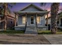 Evening view of a charming single-story home with a quaint front porch and well-maintained landscape at 2317 W Chestnut St, Tampa, FL 33607