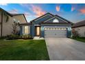 Inviting blue home showcasing a manicured lawn and a two-car garage at dusk at 30647 Walker Cup Pl, Wesley Chapel, FL 33543