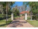 Gated driveway leading to a luxury home with mature trees and landscaping at 3607 Berger Rd, Lutz, FL 33548