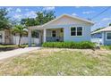 Charming blue bungalow with a covered porch, yellow front door, and an attached garage at 7113 S Mascotte St, Tampa, FL 33616