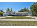 Single-story home boasts lush lawn, circular driveway, and vibrant front door at 827 Virginia St, Dunedin, FL 34698