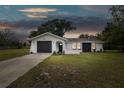 Charming single-story home boasts a modern exterior with a well-maintained front yard at dusk at 8512 Longboat Ln, Hudson, FL 34667