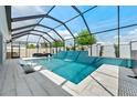 The pool features a unique waterfall feature, in-pool loungers, and a screened enclosure, offering privacy and shade at 8720 Drummer Plank Dr, Wesley Chapel, FL 33545