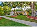 Inviting home showcasing lush green lawn, mature shade trees, and an attached garage for convenient parking at 12024 Stone Crossing Cir, Tampa, FL 33635