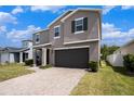 Two-story home with a gray exterior, brick-paved driveway, two-car garage, and manicured front lawn at 13802 Kinsale St, Riverview, FL 33579