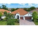 Aerial view of a single-story home featuring a red tile roof, paver driveway, and lush landscaping at 16913 Clear Cork Dr, Wimauma, FL 33598