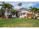 Inviting home exterior featuring lush landscaping and a charming facade with a two-car garage at 1793 Pipers Meadow Dr, Palm Harbor, FL 34683