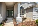 Cozy front porch featuring a stone walkway, accent seating, and well-manicured landscaping at 1793 Pipers Meadow Dr, Palm Harbor, FL 34683