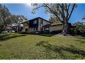 Exterior side view of a well maintained home with a spacious lawn area shaded by a large tree at 1836 Bough Ave # C, Clearwater, FL 33760