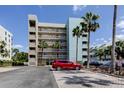 Exterior view of the condo building with palm trees and parking lot in Madeira Beach at 19925 Gulf Boulevard # 502, Indian Shores, FL 33785