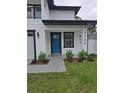 Close up of front porch with blue door, modern fixtures, landscaping and the address number at 5730 66Th Ln N, St Petersburg, FL 33709