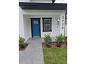 Close up of front porch with blue door, modern fixtures, landscaping and the address number at 5730 66Th Ln N, St Petersburg, FL 33709