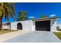 Lovely home showing the facade with a unique arched entrance, two-car garage, and well-manicured front yard at 6311 Seabreeze Dr, Port Richey, FL 34668
