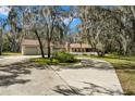 Charming home with a long driveway and mature trees covered in Spanish moss, adjacent to a separate two car garage at 6718 Watson Rd, Riverview, FL 33578