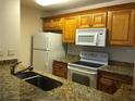 Classic kitchen featuring wood cabinets, granite countertops, and white appliances at 10114 Winsford Oak Blvd # 517, Tampa, FL 33624