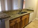 Kitchen featuring wood cabinets, granite countertops, stainless steel sink, and white appliances at 10114 Winsford Oak Blvd # 517, Tampa, FL 33624