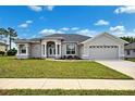 Charming single-story home with manicured lawn and neutral stucco exterior under a clear blue sky with fluffy white clouds at 13096 Linzia Ln, Spring Hill, FL 34609