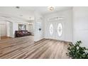 Bright foyer with stylish front doors, wood floors, and view into the living space with leather sofa and arched doorway at 13096 Linzia Ln, Spring Hill, FL 34609