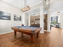 Well-lit game room with a pool table, hardwood floors, decorative wood wall, and view into living space at 14209 Quintessa Ln, Lithia, FL 33547