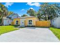 Inviting yellow home with a large driveway, manicured lawn, and natural wooden fence at 1432 19Th S St, St Petersburg, FL 33712