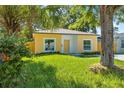 Quaint yellow home featuring lush green grass, mature trees, and charming, neutral trim at 1432 19Th S St, St Petersburg, FL 33712