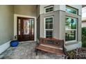 Inviting front porch area with an elegant stained-glass front door and a comfortable bench at 1522 Riverdale Dr, Oldsmar, FL 34677