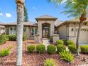 Home's front entrance featuring stone accents, manicured landscaping, and a decorative wood and glass front door at 16529 Ivy Lake Dr, Odessa, FL 33556