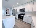 Modern kitchen boasts white cabinets, stainless steel appliances, and quartz countertops at 3329 Roxbury Dr, Holiday, FL 34691