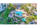 An aerial view of a community pool, complete with lounge seating, shaded tables, and lush landscaping at 400 Island Way # 201, Clearwater Beach, FL 33767