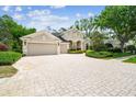 Charming home showcasing a three car garage, elegant architecture, and a beautifully bricked driveway at 1655 Eagles Reach, Tarpon Springs, FL 34688